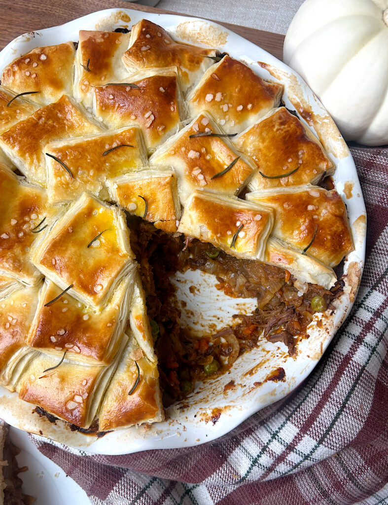 a pie plate with a shredded meat filling and golden pastry top