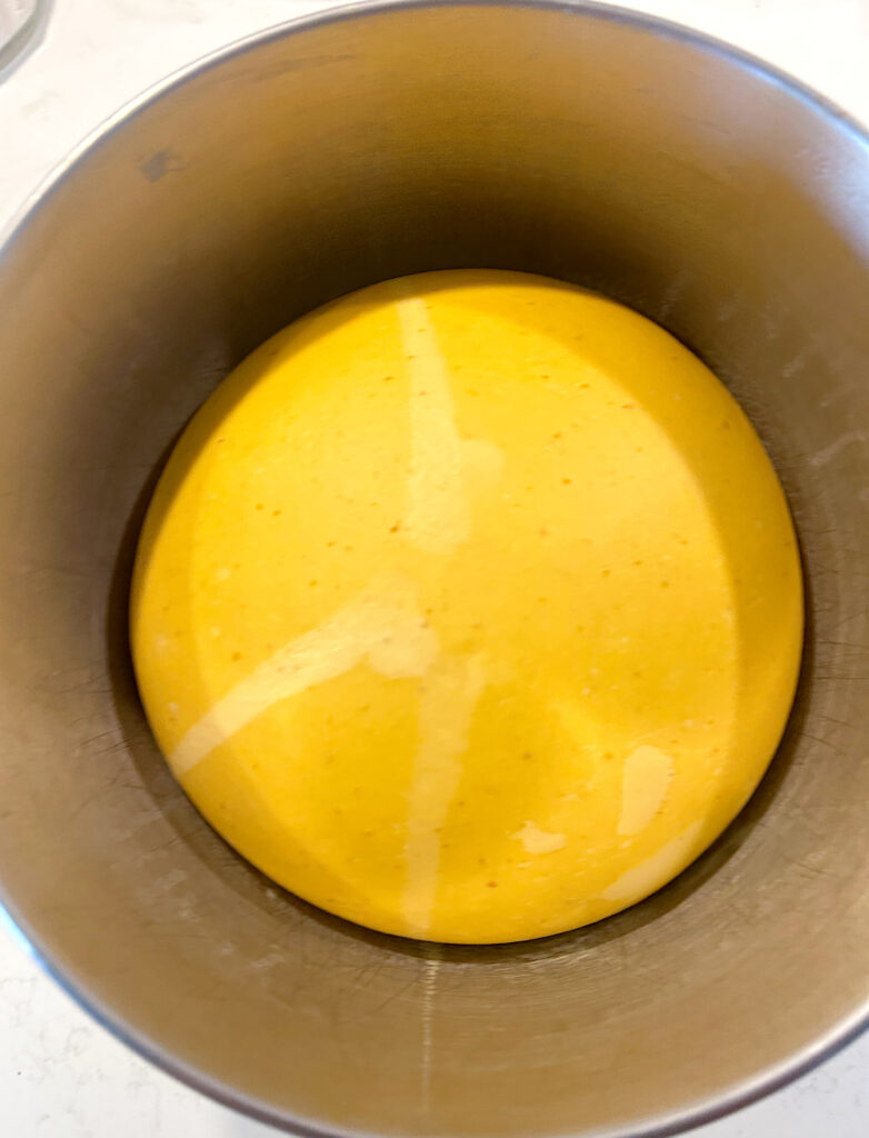 a stainless bowl of pumpkin bread dough