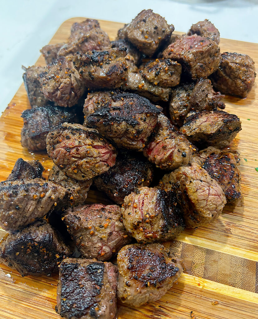 little cubes of seared steak on a wood board