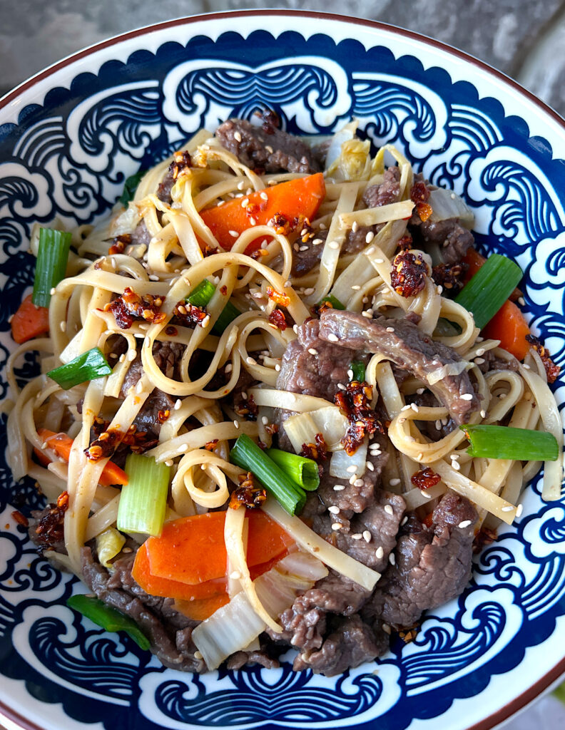 a blue and white bowl full of homemade chow mein made with venison