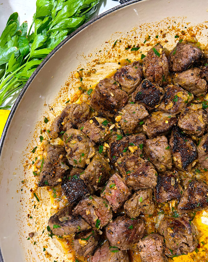 a skillet of little cubes of steak in cowboy butter sauce