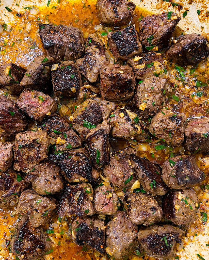 a skillet of seared cubes of steak in a butter sauce