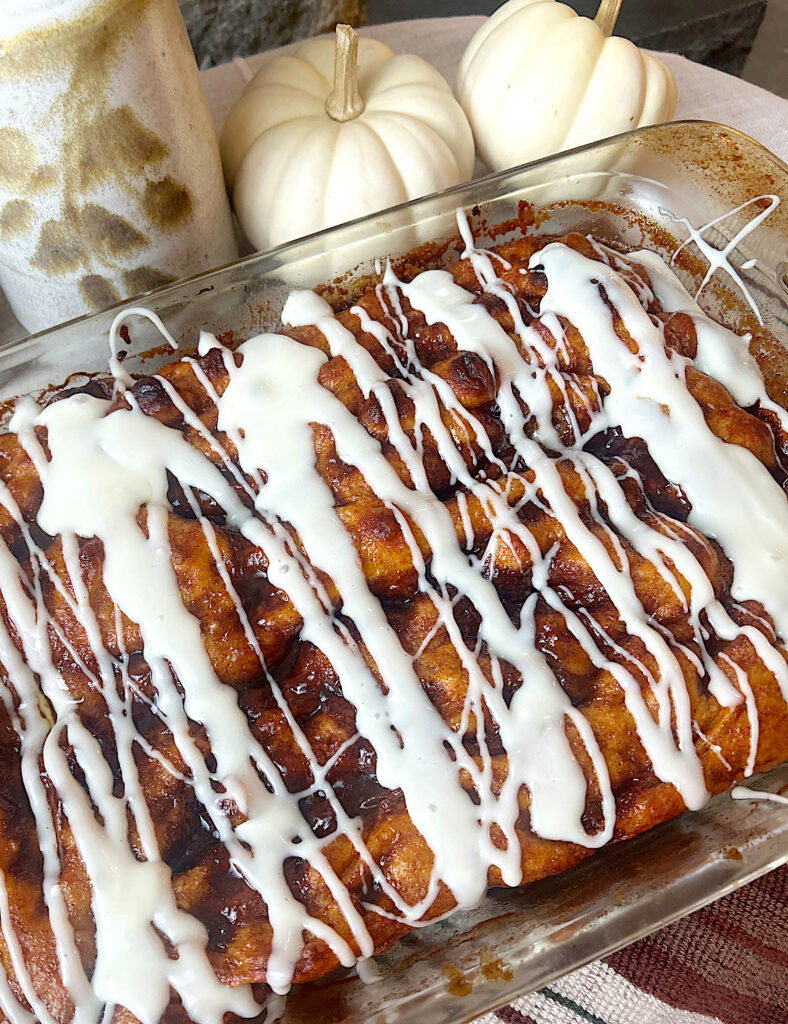 a tray of baked pumpkin focaccia bread with cinnamon will and cream cheese icing