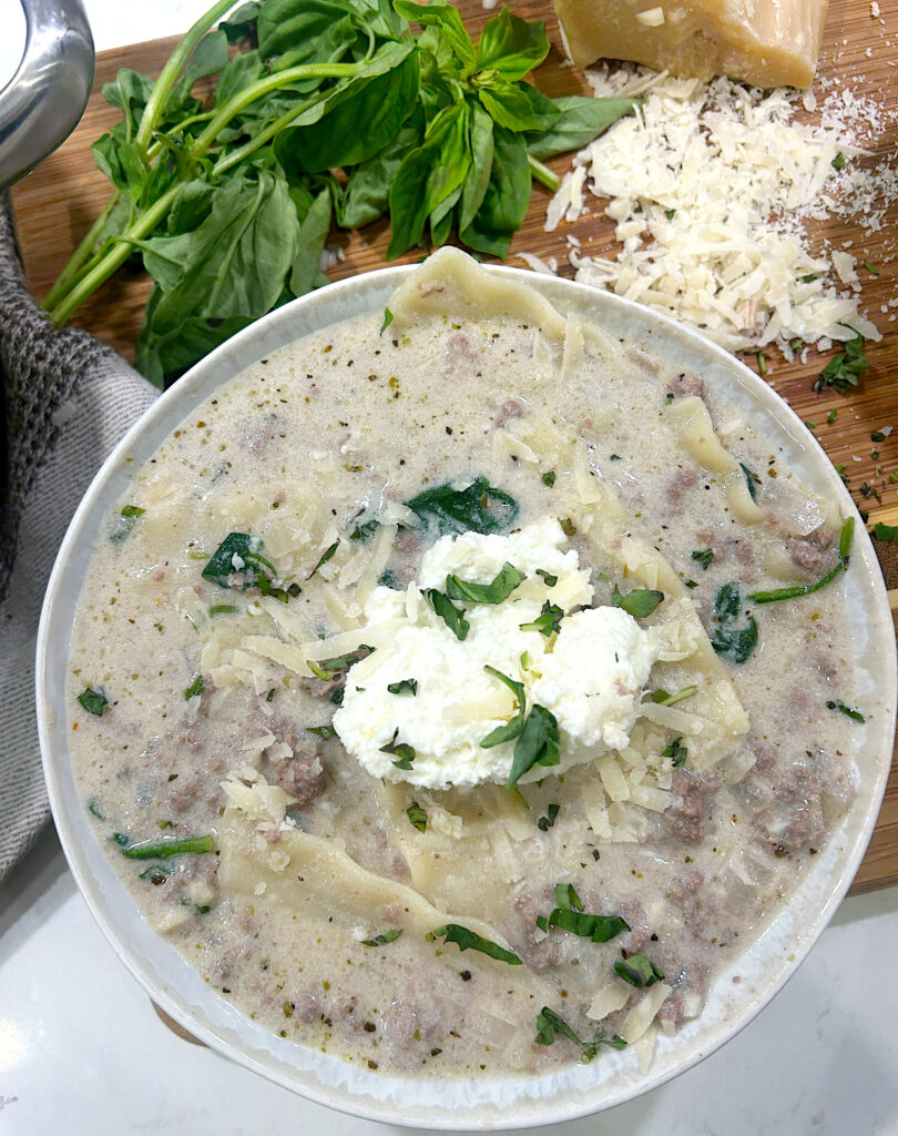 a bowl of creamy soup with noodles and ground venison and ricotta cheese on top